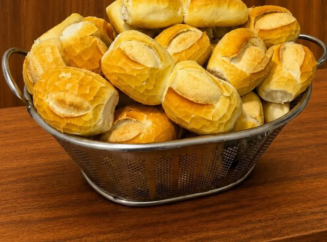 Cesto de pães franceses dourados sobre a mesa de madeira